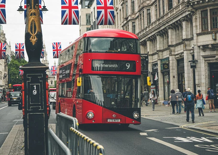 Iconic red double-decker bus on a busy street in London, England, with British flags overhead. - iptv uk