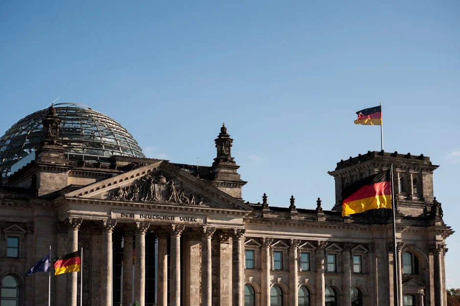 Historic Reichstag building in Berlin with prominent German flags displayed under a clear blue sky. - iptv deutschland