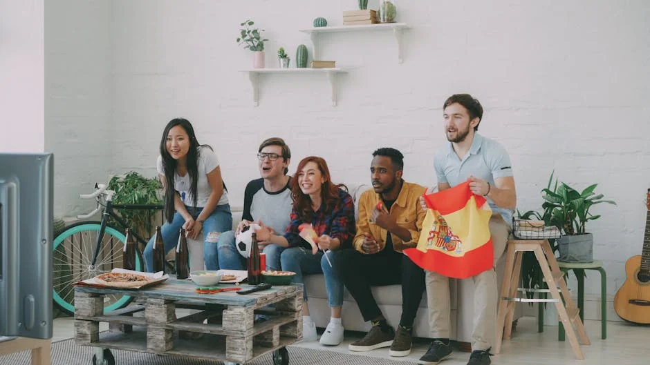 A group of friends eagerly watching sports on TV, holding a Spanish flag, indoors. - iptv espaa