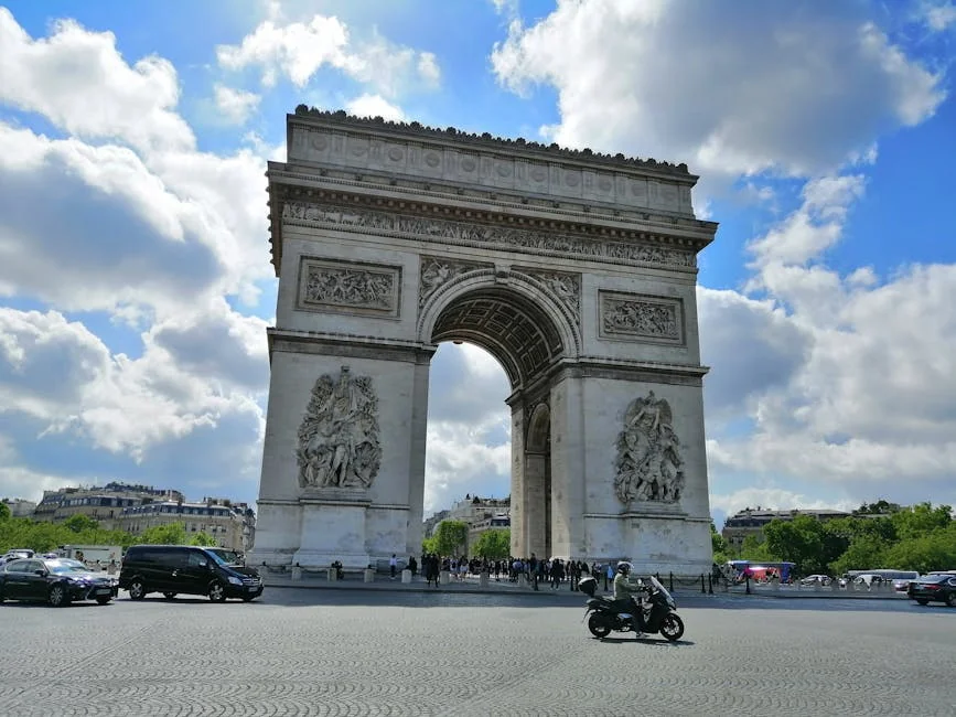 The iconic Arc de Triomphe stands tall under a bright, cloudy sky in Paris. - iptv france