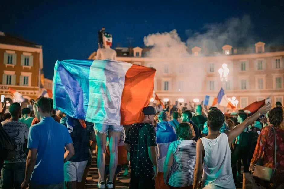 Vivid night-time celebration in France with crowds waving flags in city square. - iptv france