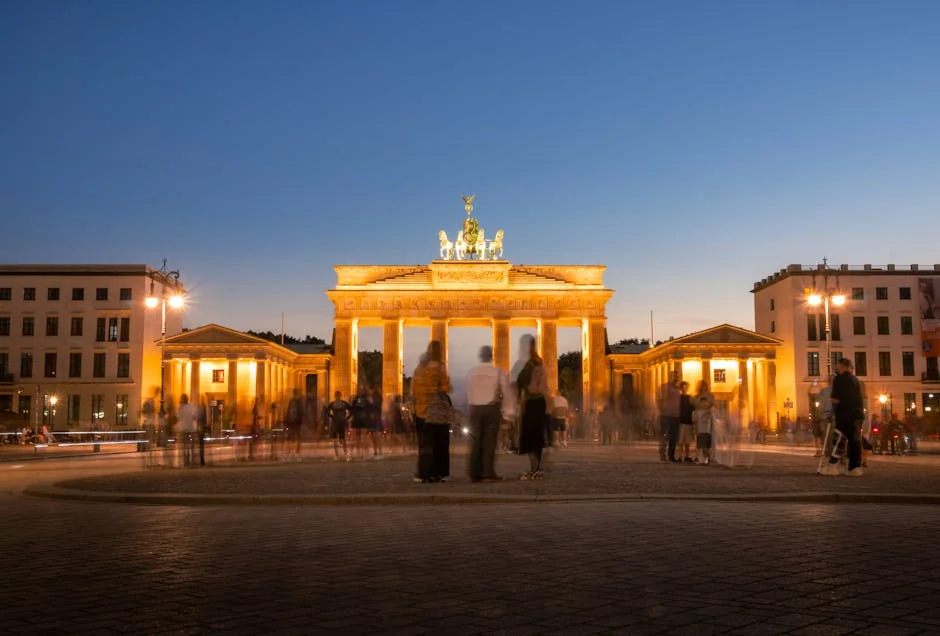 People gather by the illuminated Brandenburg Gate in Berlin at twilight. - iptv m3u germany 4k