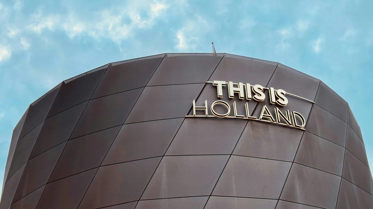Close-up of the modern “THIS IS HOLLAND” building facade in Amsterdam, capturing sleek architecture under a bright sky - iptv netherlands