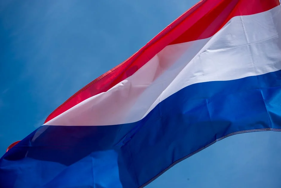 A dynamic shot of the Netherlands flag waving against a clear blue sky, symbolizing freedom and patriotism. - iptv netherlands