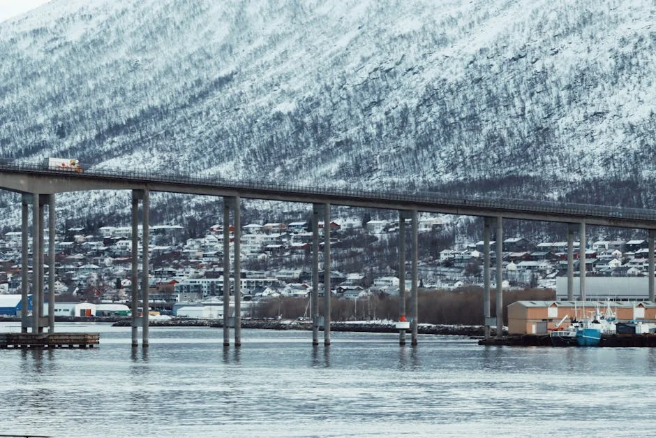 Scenic view of Tromsø Bridge with snowy mountains and calm waters, capturing winter in northern Norway. - iptv nordic