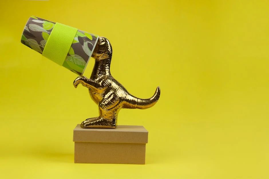 Small golden T Rex statuette with paper cup on head on cardboard box and on bright yellow background - trex iptv